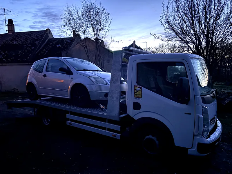 Citroën C2 chargée sur la dépanneuse à la tombée de la nuit